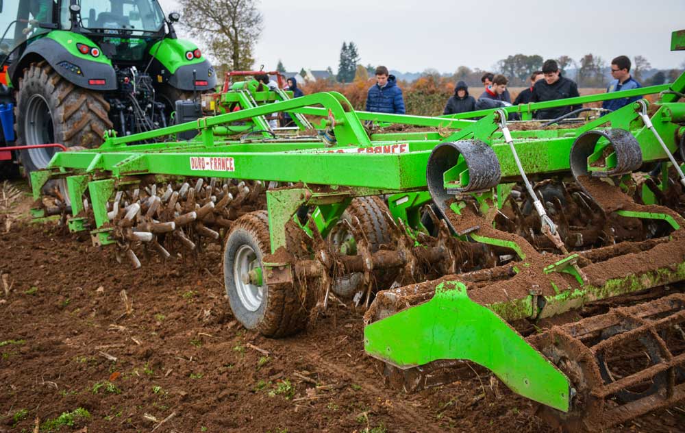 L’axe des trains de bêches forme un angle léger par rapport à l’axe d’avancement du tracteur : il s’en suit un déplacement latéral des bêches lors de la progression de l’outil. En associant l’avancement et le mouvement latéral, la pointe de la bêche décrit un arc de cercle entre sa pénétration dans le sol et sa sortie. Il en résulte un mouvement d’arrachement en « coup de cuillère ». - Illustration La Cuma de l&rsquo;espoir mise sur un déchaumeur Duro Compil