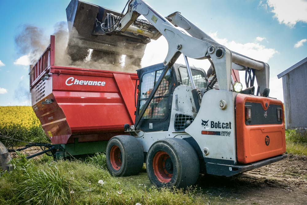 Grâce à son godet spécifique, le S770 réussit à lever assez haut pour charger les remorques agricoles. - Illustration Chargeuses compactes : Puissance et maniabilité pour vider les bâtiments