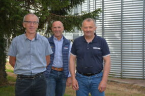 3 personnes devant une cellule de stocakge de blé