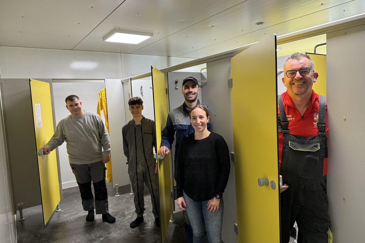 Quatre hommes et une femme présentent les nouveaux vestaires d'un élevage de porc. - Illustration Se projeter sur le long terme dans l’entreprise