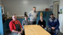Quatre hommes et une femme travaillant dans une salle de pause.