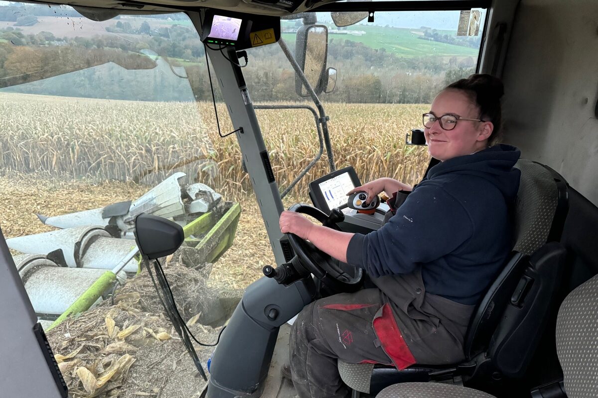 Une jeune femme au volant dans une cabine de moissonneuse - Illustration « La conduite, c’est mon truc »