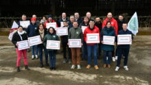 Les membres de la liste portent des panneaux et drapeaux devant une stabulation
