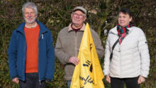 Deux hommes et une femme retraités avec un drapeau jaune du syndicat agricole de la Confédération paysanne