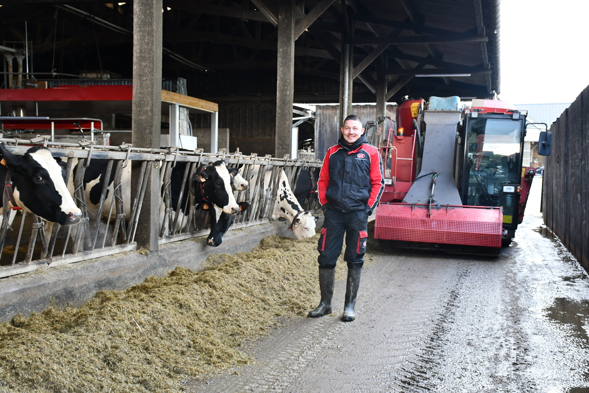 Alexis Robert devant la mélangeuse dans le couloir d'alimentation avec les vaches - Illustration L&rsquo;automotrice rationalise la distribution