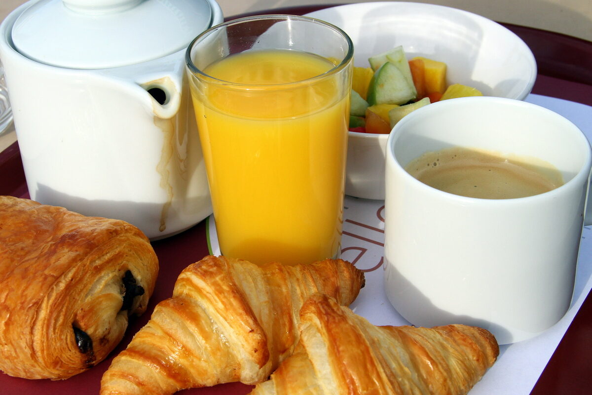PETIT DÉJEUNER AVEC CAFÉ, JUS D'ORANGE ET PAIN AU CHOCOLAT - Illustration Quand le petit-déjeuner nous ramène à la réalité !
