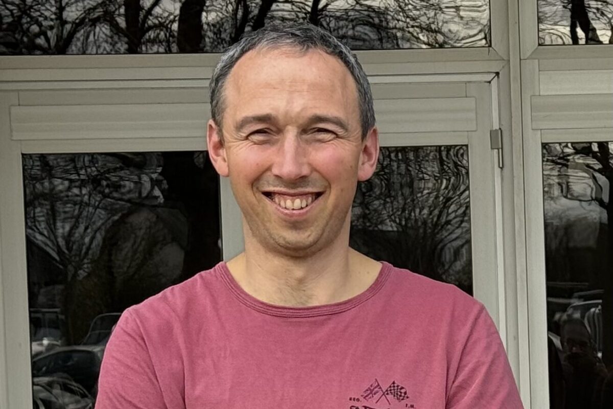 un homme souriant les bras croisés devant un bâtiment - Illustration David a trouvé la ferme de ses rêves au RDI