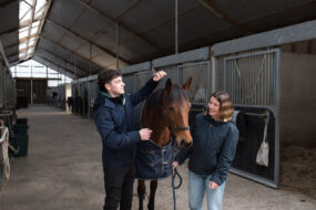 Un étudiant et une étudiante avec un cheval.