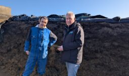 2 hommes devant un ensilage d'herbe