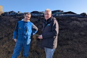 2 hommes devant un ensilage d'herbe