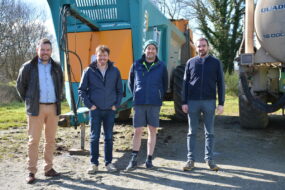 Quatre hommes devant du matériel agricole