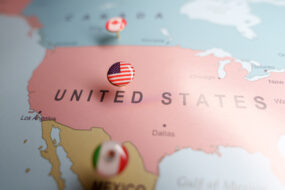 Une carte des USA, Mexique et Canada avec des punaises aux couleurs des drapeaux respectifs