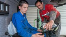 Un agriculteur en train de former un jeune dans une cabine de tracteur