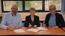 Trois personnes signent un partenariat