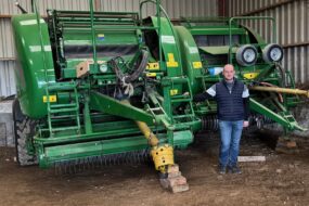Un éleveur devant deux outils pour presser de l'herbe.