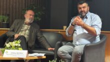 Deux hommes assis lors d'une table ronde.