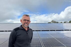 Un homme devant un champ de panneaux solaires en toiture