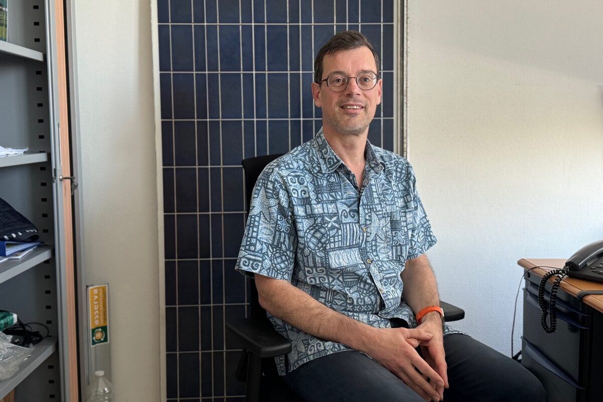 Un homme assis devant un panneau solaire - Illustration Les batteries vont venir booster l’autoconsommation