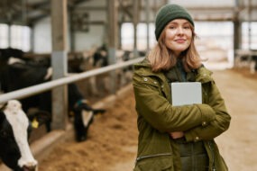 Portrait d'une jeune femme agronome avec une tablette debout dans une stabulation avec des vaches
