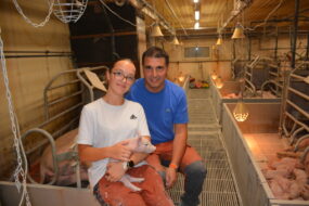 Un homme et une jeune fille souriants dans un élevage de porc