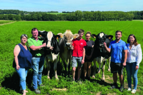 Une famille d'éleveurs présente deux vaches Holstein et une vache Brune.
