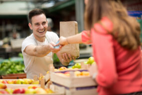 Un commerçant sur un marché de fruits et légumes qui prend la monnaie d'une cliente