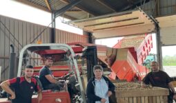 Trois hommes et une femme sous un hangar de réception et de tri de pommes de terre.s