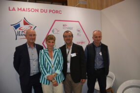 Quatre personnes posent sur le stand de la maison du porc sur un salon