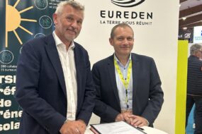 deux hommes souriants sur un salon prennent la pose