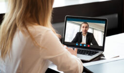 une femme de dos devant un écran d'ordinateur portable en visioconférence avec un homme