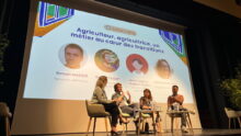 Quatre personnes sur une scène lors d'une conférence avec un grand écran derrière