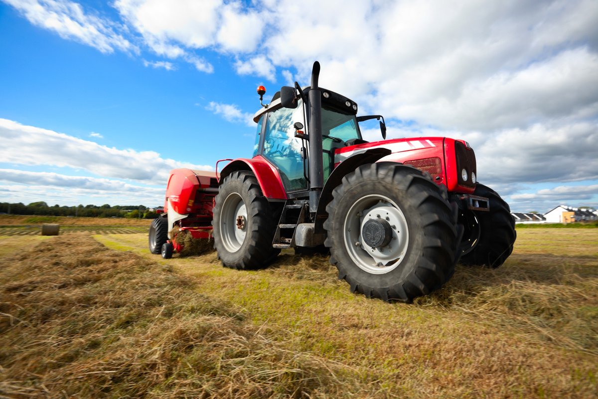 Un tracteur au travail dans un champ avec une presse - Illustration Prêter son tracteur à un particulier : une fausse bonne idée ?