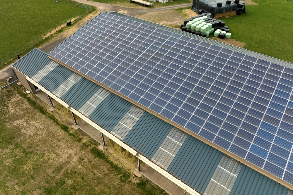 Vue aérienne d'une couverture de bâtiment agricole recouverte de panneaux photovoltaïques - Illustration Produire, consommer  et protéger  son énergie solaire