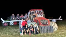 Des jeunes agriculteurs autour d'une structure de paille représentant un tracteur avec des ailes