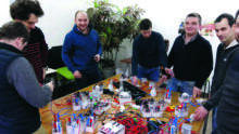 Des hommes autour d'une table avec du matérile d'électricité posé dessus