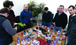 Des hommes autour d'une table avec du matérile d'électricité posé dessus