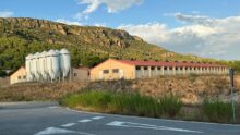 Un paysange de montagne ensoleillé avec un bâtiment d'élevage de porc et des silos à grain