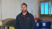 Un homme dans un atelier avec une roue de tracteur derrière