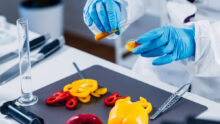 Gros plan sur les mains d'un scientifique qui porte des gants de laboratoire. Il analyse des poivrons