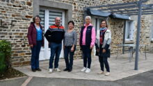 Des personnes devant une maison d'habitation en vieilles pierres