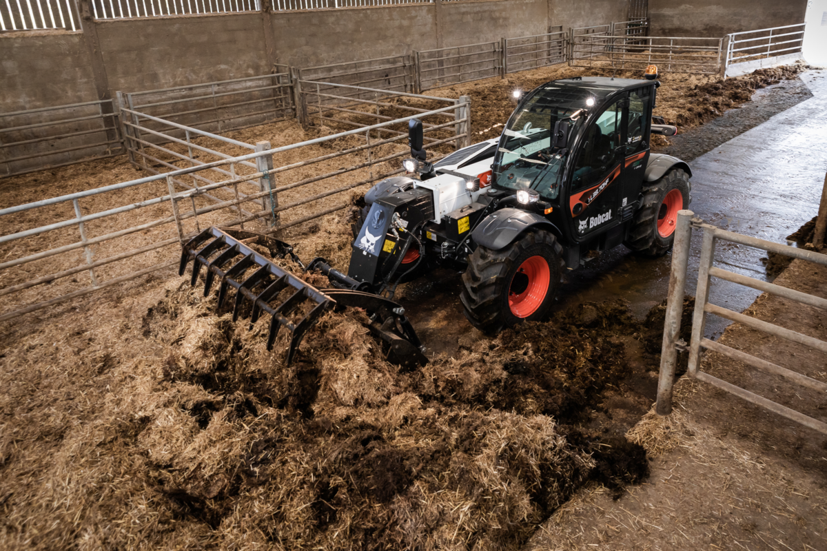 Un chariot télescopique équipé d'un godet à griffes en train de curer une stabulation - Illustration La location du télesco fait ses preuves