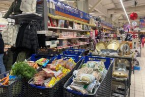Trois caddy remplis de produits alimentaires dans un magasin de grande distribution
