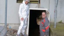 Deux personnes devant le système de chauffage d'une porcherie