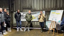 Des hommes rassemblés dans un bâtiment d'élevage laitier