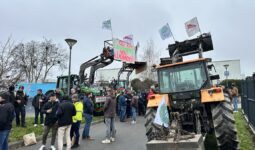 Des manifestants avec des drapeaux et des pancartes accrochés sur des tracteurs