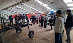 Des personnes dans un hangar autour de machines agricoles