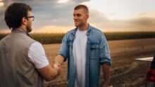 Un agriculteur serre la main d'un partenaire dans un champ