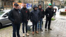 Cinq hommes sur un trottoir par un temps pluvieux