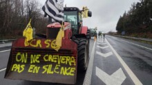Un tracteur avec un godet et une inscription jaune "on ne crèvera pas en silence" dans le godet