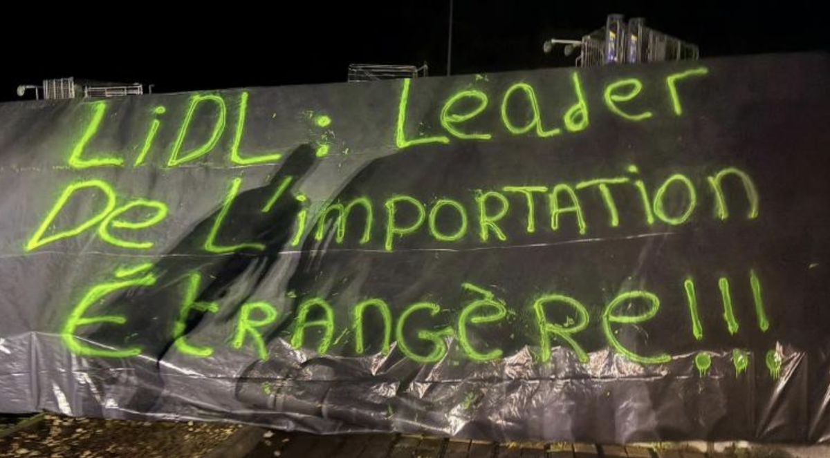 Un panneau avec une inscription dessus ; Lidl ; Leader de l'importation étrangère - Illustration Les JA ciblent le « leader  des importations étrangères »